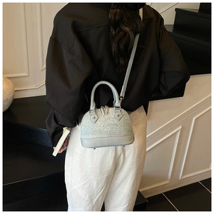 Close-up of light blue shell crossbody bag with sparkling rhinestone details and top handle