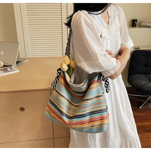 Detail of colorful woven straw tote bag with striped fabric straps for beach vacations