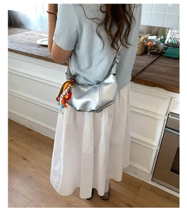 Silver crescent shoulder bag with knot strap detail and colorful tassel on model