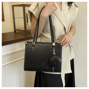 Detail of black embossed tote bag with circular coin purse and gold-tone hardware detail