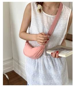 Détail d'un sac demi-lune en nylon rose clair avec large bandoulière sur un mannequin