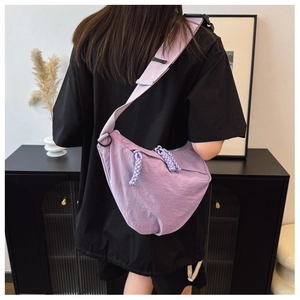 Dettaglio della larga tracolla regolabile e della borsa a mezzaluna viola su un modello