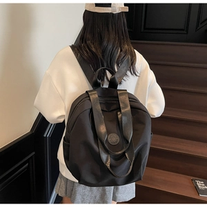 Rückansicht eines minimalistischen schwarzen Nylon-Rucksacks mit Seitentaschen an einem Modell