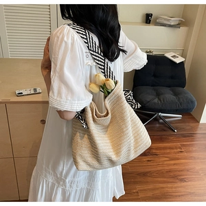 Detail of bohemian straw woven tote bag with black and white striped shoulder strap