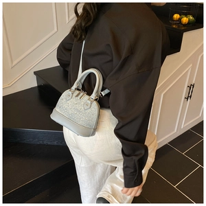 Détail du sac coquille bleu clair avec texture cloutée et finitions dorées sur modèle