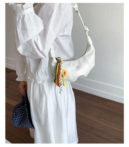 Detail of white hobo bag with braided rope handle and colorful smiley face charm
