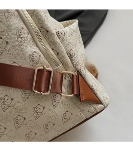 Detail showing adjustable brown nylon shoulder strap with gold metal buckle on printed bag