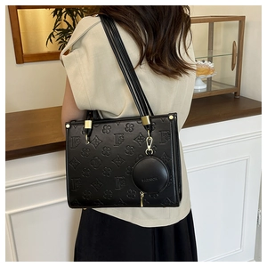 Detail of black tote bag featuring floral embossed F pattern and fashion hanging charm
