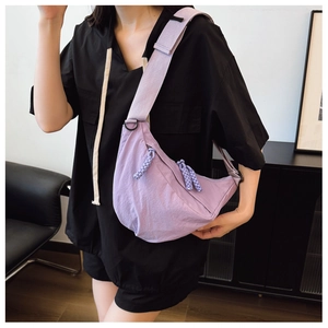 Borsa a tracolla a mezzaluna in nylon viola con ampia tracolla indossata da modella