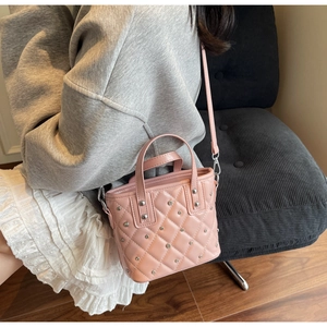 Detail der rosa gesteppten Beuteltasche mit silbernen Nieten, von einem Model getragen