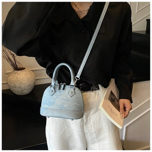 Détail du sac bandoulière bleu clair à paillettes scintillantes et base en cuir