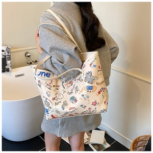 Detail of white graffiti tote bag with colorful text prints on a model shoulder