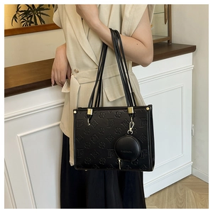 Close-up of black embossed leather tote bag with gold hardware and fashion pendant