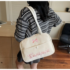 Detail of cream tote bag featuring pink bow and Gugiigugii embroidery with front pocket