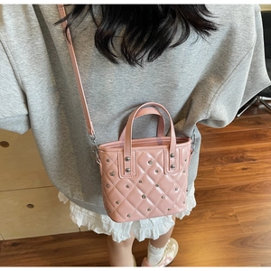 Lifestyle shot of pink quilted bucket bag with silver studs worn as a crossbody purse