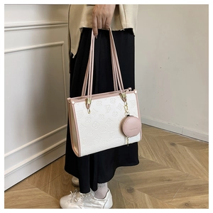 Detail of color-block tote bag with floral embossing and a pink mini hanging pouch