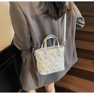 Detailaufnahme einer gesteppten Eimertasche mit Nieten, von einem Model getragen