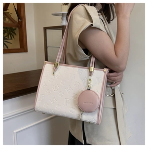 Detail of elegant beige tote bag with pink trim, embossed floral pattern and coin purse