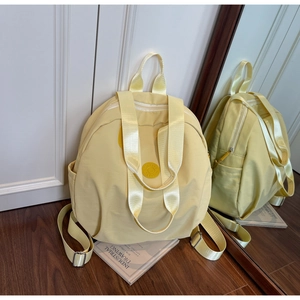 Detailansicht des gelben Nylon-Rucksacks mit Seitentaschen und einem robusten Tragegriff
