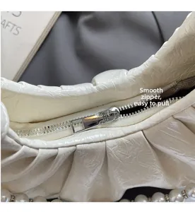 Detailed shot of the smooth silver zipper and glossy ruched fabric of the cloud bag