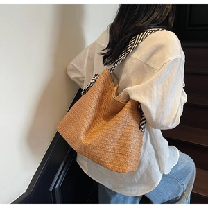 Detail of bohemian straw bag featuring black and white striped scarf on the handle