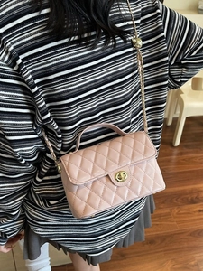 Pink quilted crossbody bag with gold chain strap and top handle in a lifestyle setting