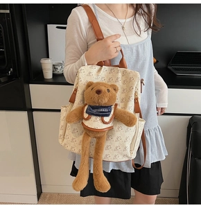 Detail of cream canvas backpack with bear prints and a hanging plush bear toy