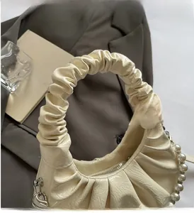 Close-up of cream ruched handbag featuring elegant pearl chain and soft texture