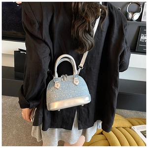 Detail of silver-blue glitter shell bag with metallic handles worn by a model