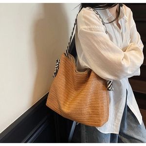 Close-up of caramel straw tote bag with black and white braided rope shoulder strap