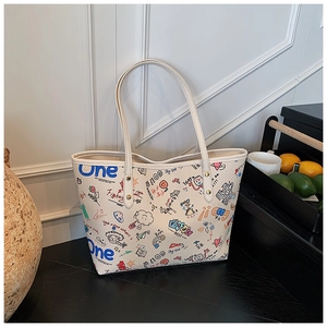 Détail d'un sac cabas en cuir crème avec des graffitis colorés et des rivets dorés
