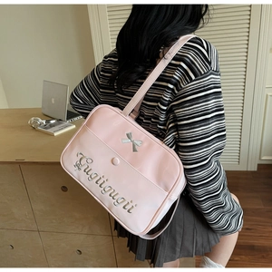 Pink JK style shoulder bag with silver bow embroidery shown in a lifestyle study setting