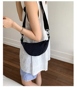 Détail d'un sac demi-lune en nylon noir avec bandoulière réglable porté par un modèle