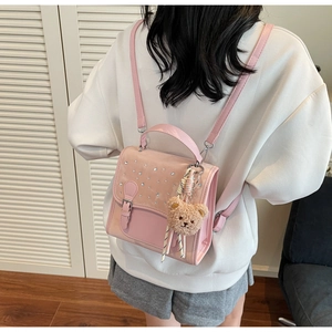 Close-up of pink fashion backpack with rhinestone decor and plush bear charm detail