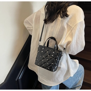 Detail der schwarzen gesteppten Beuteltasche mit Nieten am Model auf der Treppe