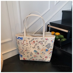 Gros plan d'un sac cabas beige avec des graffitis colorés et de fines bandoulières doubles