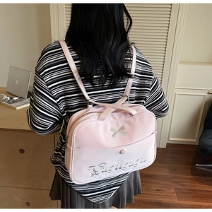 Pink JK style nylon bag with silver bow embroidery and letter detail shown in study setting