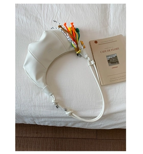 Macro detail of white crescent bag with colorful braided tassel and rope strap