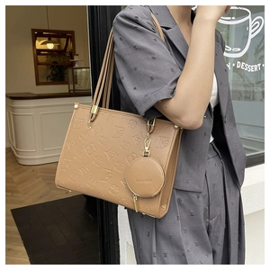 Macro detail of khaki leather tote with clover embossing and fashion pendant