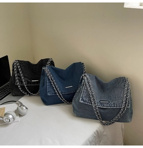Detailed shot of large denim tote bags in black and blue with metal chain straps