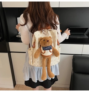 Detail of beige printed backpack with cute plush bear pendant and leather accents