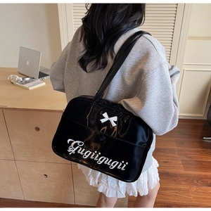 Detailed view of large black glossy tote bag with white bow and Gugigugii embroidery