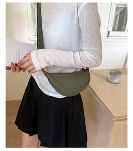Sac bandoulière demi-lune en nylon vert armée porté par un mannequin en décor épuré