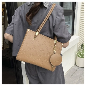 Detail of tan embossed tote bag with floral patterns and a fashion coin purse charm