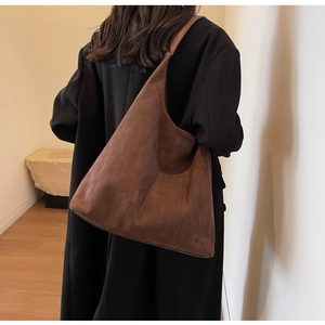 Detail van minimalistische donkerbruine suède hobo tas met textuur en drapering
