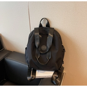 Detailansicht eines schwarzen Nylon-Rucksacks mit Logo auf einem Sofa mit Kunstbüchern