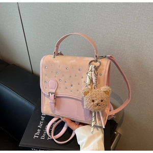 Close-up of pink multi-functional backpack with rhinestones and a plush bear charm