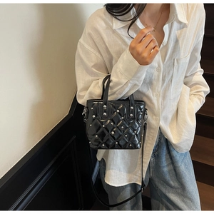 Detailed close-up of glossy black diamond quilted mini tote with silver studs and straps