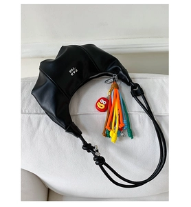 Detail of black crescent shoulder bag with PAN 'TOR logo and colorful tassel charm