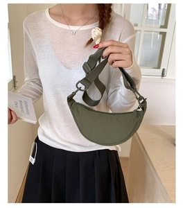 Sac bandoulière demi-lune en nylon vert foncé avec bandoulière réglable porté par un mannequin